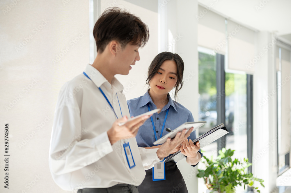 A professional Asian male worker is explaining and helping a female colleague with a project A professional Asian male worker is explaining and helping a female colleague with a project