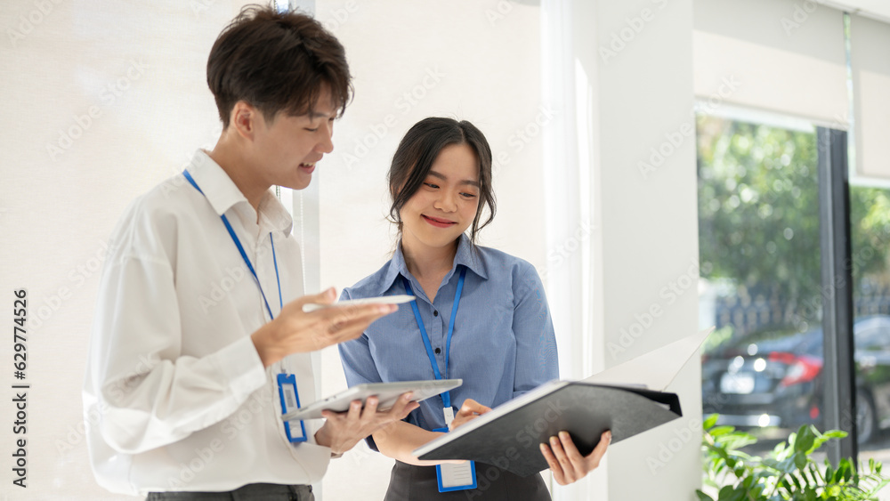 A friendly Asian male worker is explaining and helping a female colleague with a project A friendly Asian male worker is explaining and helping a female colleague with a project