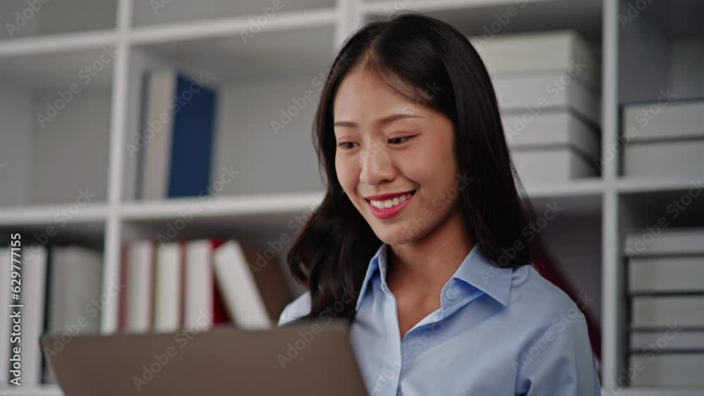 Businesswoman in blue sky shirt is working on laptop with happy face in office space. Businesswoman in blue sky shirt is working on laptop with happy face in office space.