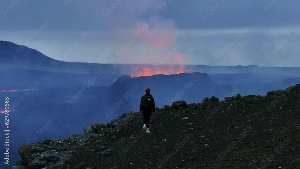 Aerial telephoto shot of a woman walking toward a Volcano crater, blue hour in Iceland Aerial telephoto shot of a woman walking toward a Volcano crater, blue hour in Iceland