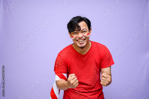 Indonesian man celebrate indonesian independence day on 17 August, expression of winning the race. isolated on purple background. copyspace