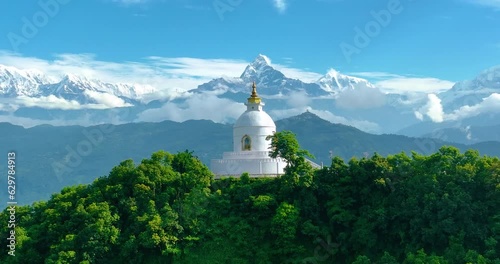 Aerial view of Peace Pagoda stupa in Pokhara Nepal. Surrounded by Beautiful mountain ranges and landscapes, Stupa stands still between the green forest. Peaceful place to meditate. 4K