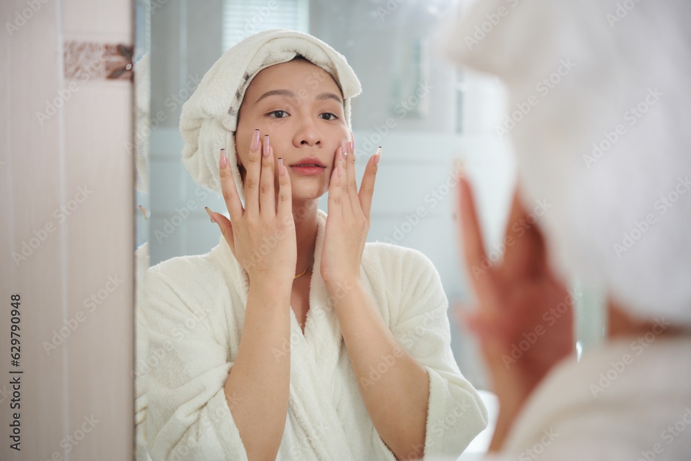 Transgender woman in bathrobe applying moisturizing lotion after morning shower Transgender woman in bathrobe applying moisturizing lotion after morning shower