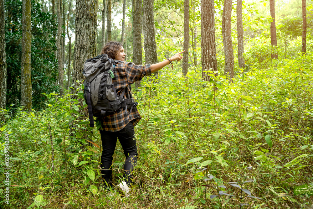 Asian woman trekking in the forest while pointing to something