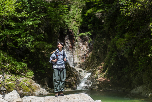 新緑の山を登山する若い日本人女性 