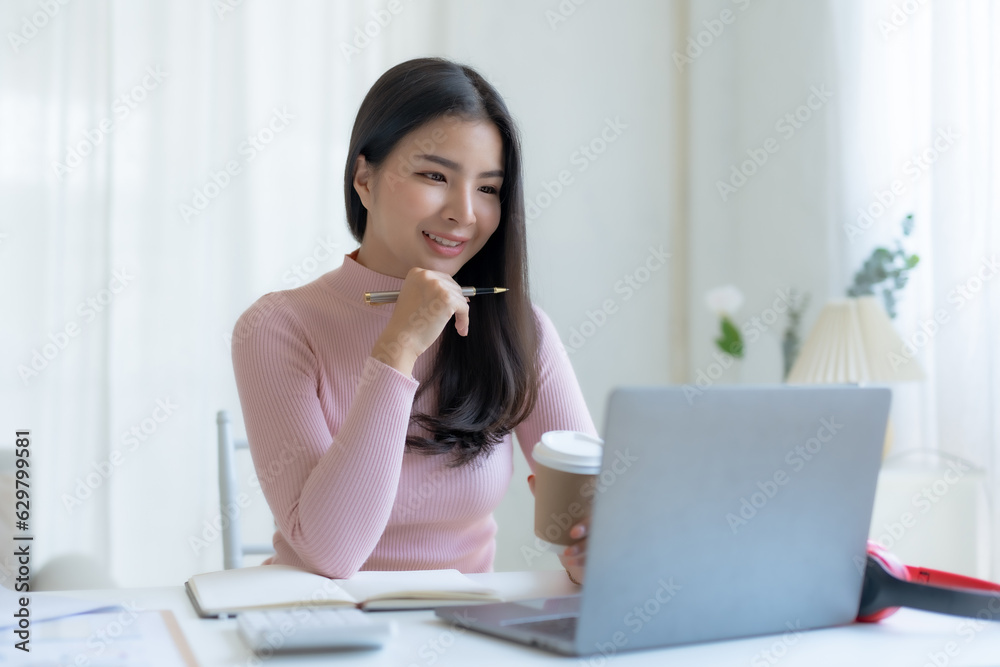 Smiling happy asian businesswoman sitting with laptop computer taking notes in office. Smiling happy asian businesswoman sitting with laptop computer taking notes in office.