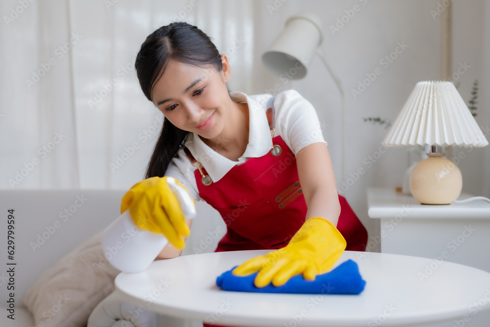 Asian housewife in gloves wearing an apron is cleaning the house happily. Happy Asian young woman working mopping the house.