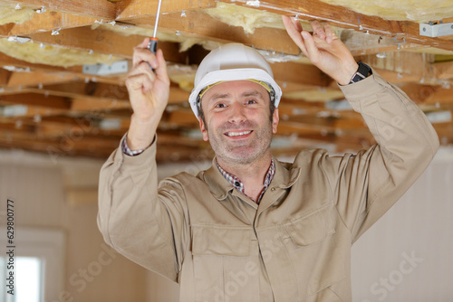 builder drives screws into ceiling of fiberboard with a screwdriver photo