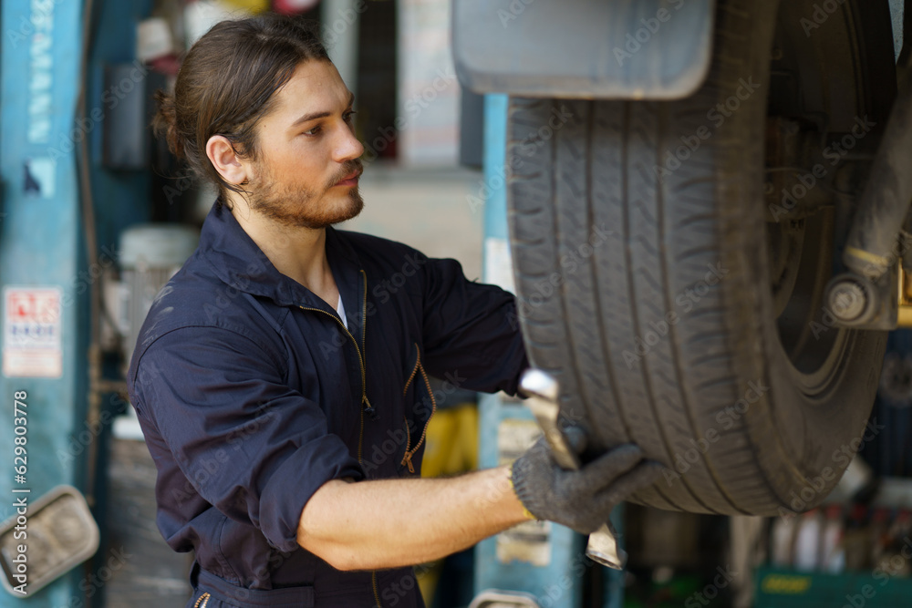 mechanic worker checking car replacing car wheel and tyre in auto repair shop store service. worker maintenance examining and installing wheel tire at garage. mechanic worker checking car replacing car wheel and tyre in auto repair shop store service. worker maintenance examining and installing wheel tire at garage.