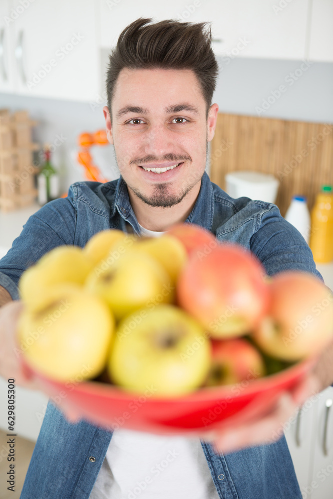 Fototapeta premium man holding bowl of apples in extended hands