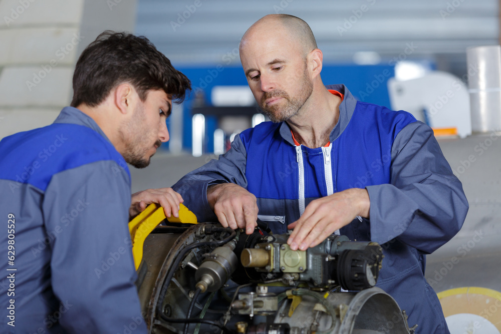 two aircraft mechanics working on engine two aircraft mechanics working on engine