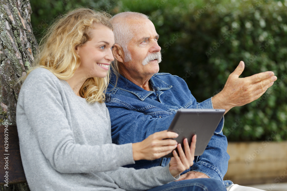 daughter with her father using tablet in the park