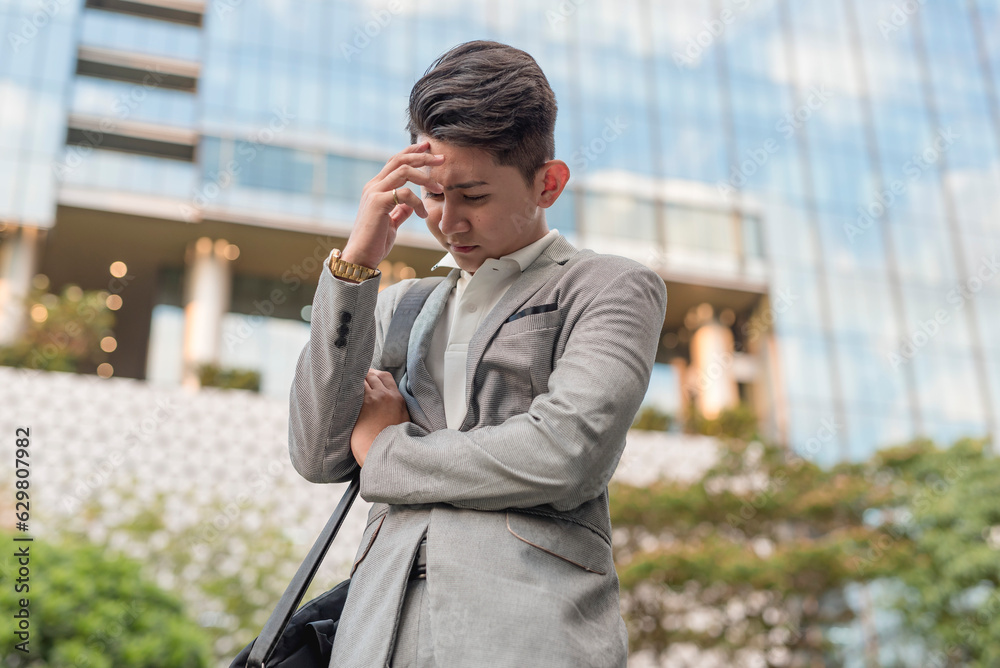 A stressed young man mulls over stressful problems at work, his hand on his forehead. Troubled after a long day at the office. A stressed young man mulls over stressful problems at work, his hand on his forehead. Troubled after a long day at the office.