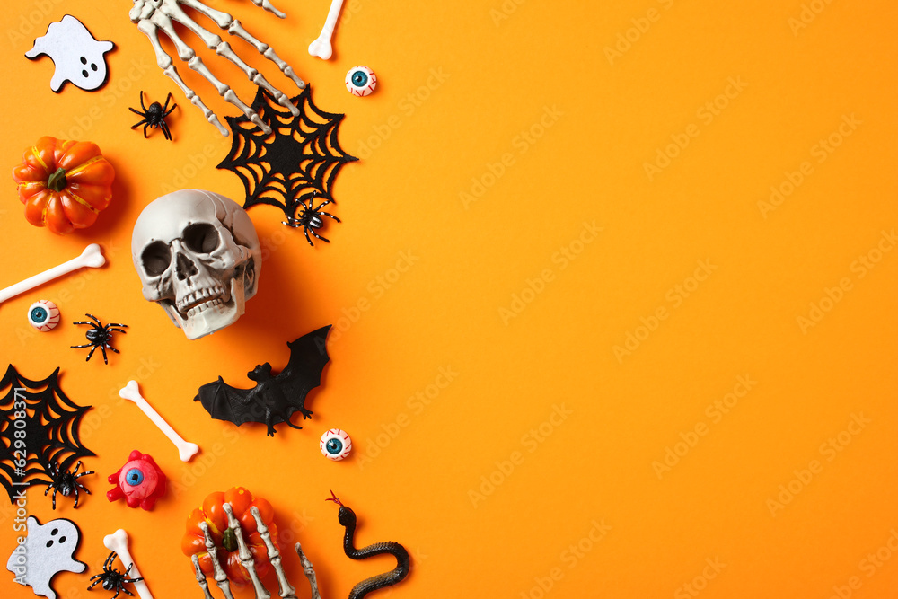 Obraz premium Halloween flat lay composition with skull, spiders, pumpkins, ghosts, skeleton hands on orange background.