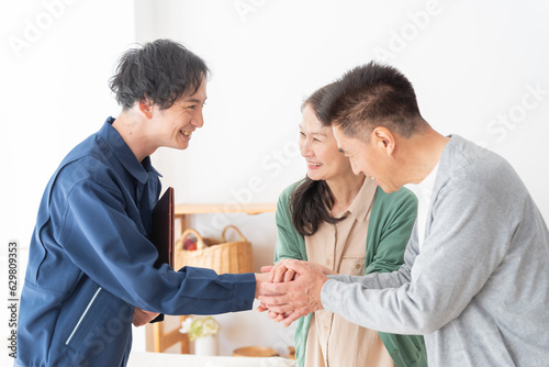 握手する業者と高齢者夫婦（引越し・内見・見積り・相談）