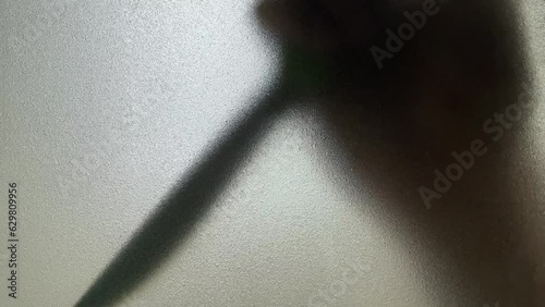 Male hand silhouette shadow behind translucent mirror holding knife moving slowly 