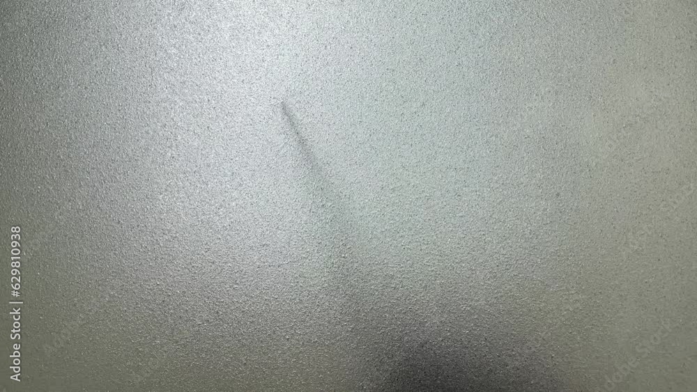 Male hand silhouette shadow behind translucent mirror holding knife moving slowly 