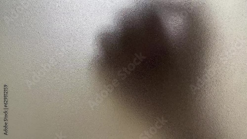 Male hand silhouette shadow behind translucent mirror knocking on glass