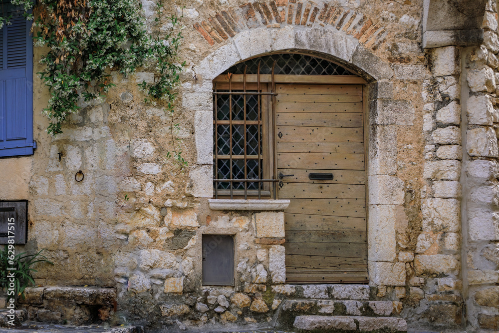 Old wooden door of a traditional stone house on a street in the medieval town of Saint Paul de Vence, French Riviera, South of France Old wooden door of a traditional stone house on a street in the medieval town of Saint Paul de Vence, French Riviera, South of France