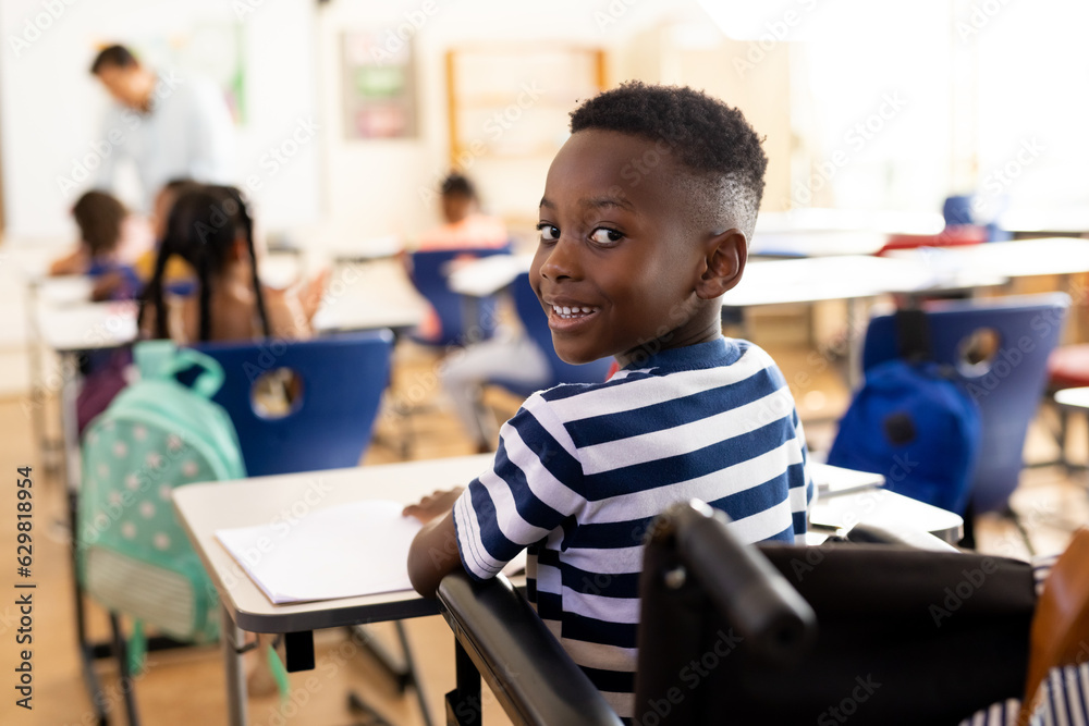 Portrait of happy african american school boy sitting in wheelchair in ...