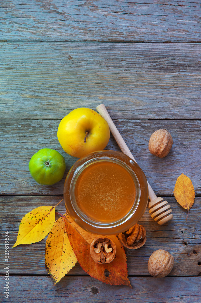 Fresh honey with pollen on an old wooden table. Autumn background with apples, walnuts and honey. Rural motive with food and fallen leaves. top view