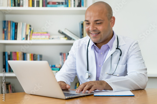 Handsome doctor with bald working at computer at office