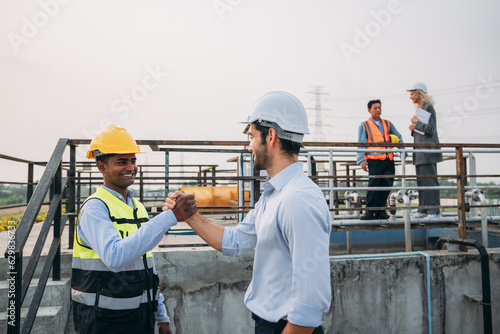 Success Stacked and Shake in a Hand. Professional Technician Ensuring Pollution Control in Wastewater Treatment Plant. Worker checking the waste water treatment pond industry.