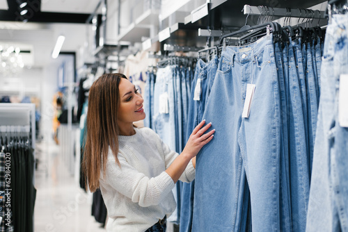 Canvastavla Caucasian woman chooses jeans, casual clothes in the store
