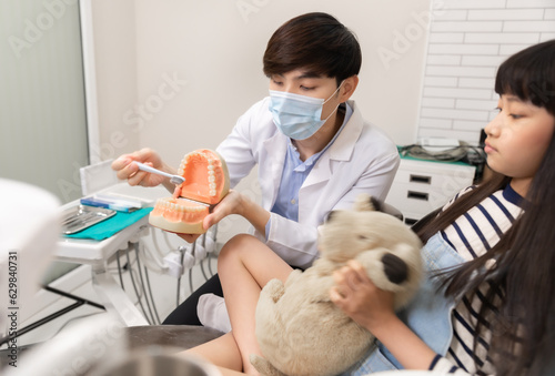 Happy asian male dentist with patient girl at clinic.Asian children's dentistry for healthy teeth and beautiful smile .