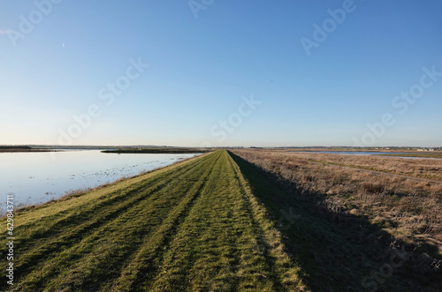 A grass trail by a lake at Wallasea Island nature reserve in Essex, UK. 