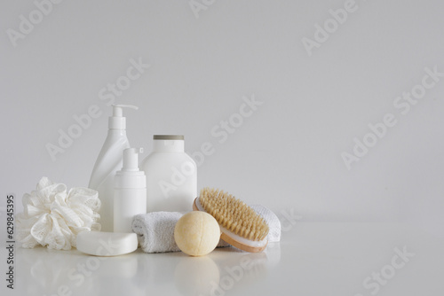 Сomposition with bath accessories, cosmetic bottles, massage brush, sponge, soap and towel with copyspace