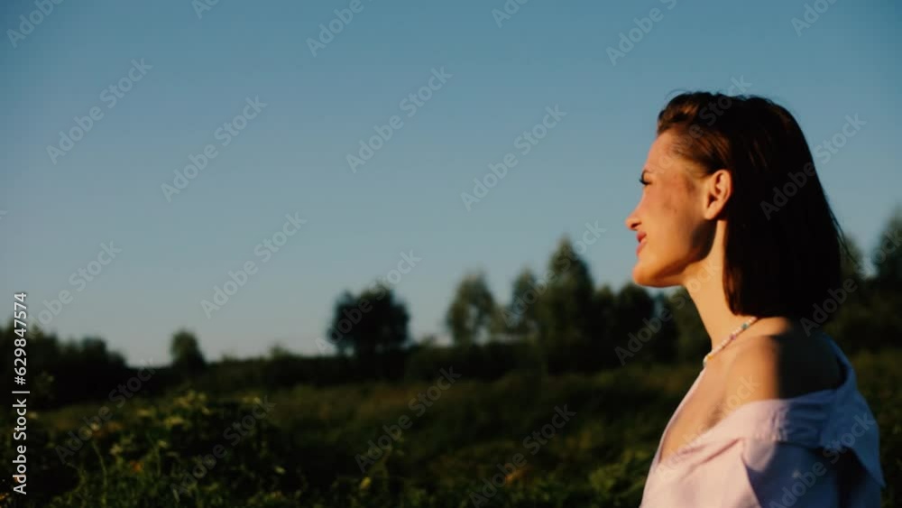 happy young woman goes walks in the summer field at sunset. happy young woman goes walks in the summer field at sunset.