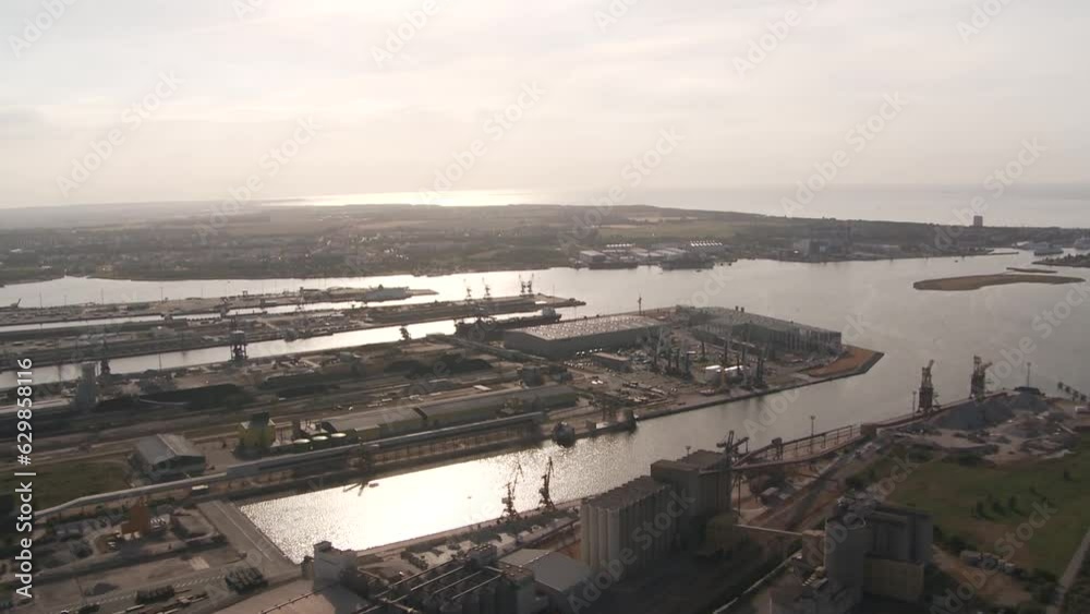 Drone shot showcases an industrial harbor bustling with ships and cranes, surrounded by buildings and roads, all presented in a stark black and white color scheme Drone shot showcases an industrial harbor bustling with ships and cranes, surrounded by buildings and roads, all presented in a stark black and white color scheme