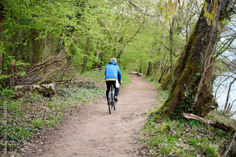 person riding a gravel bike on a forest road in France person riding a gravel bike on a forest road in France
