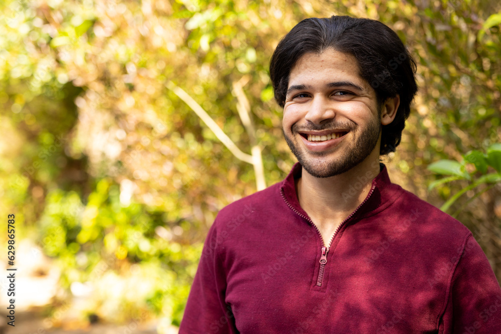 Portrait of happy indian man in sunny nature, copy space