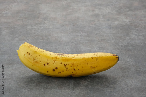 The bananas is medium ripe with brown spots all over the yellow skin. Close up and copy space.
