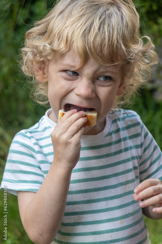 A little boy bites into a pastry A little boy bites into a pastry