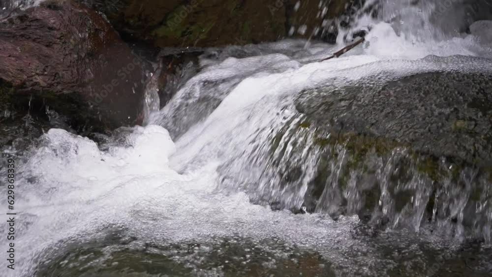 A stormy stream of a mountain stream flows through the stones. Pure water in a mountain stream is formed due to the melting of snow. A stormy stream of a mountain stream flows through the stones. Pure water in a mountain stream is formed due to the melting of snow.