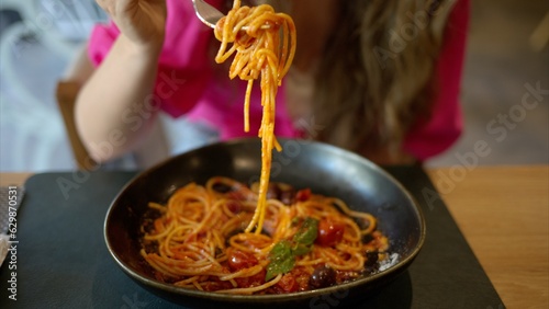 Woman eating italian pasta with basil tomatoes and olives