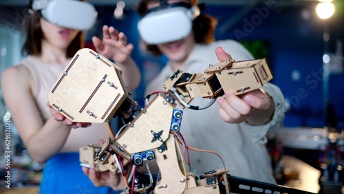 Two young engineers fixing a mechanical robot in the workshop, using VR virtual reality headsets