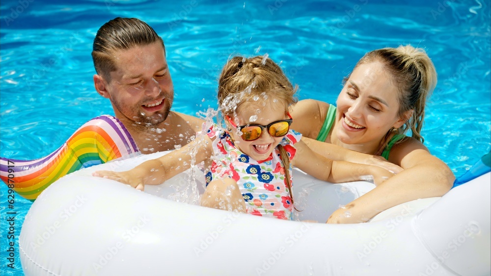 Mother with father and daughter resting and swimming in a pool in summer