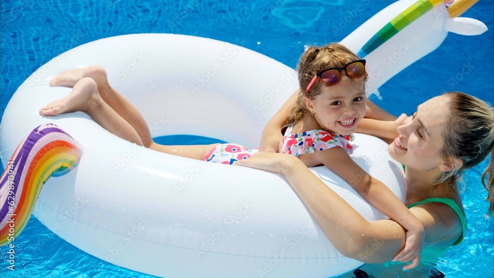 Mother and daughter resting and swimming in a pool in summer