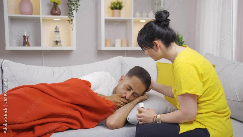 Woman giving medicine to her sick husband.