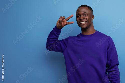 charming young african guy in a blue sweatshirt on the background with copy space
