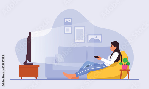 A cute girl is sitting in front of the TV with a remote control in her hands and watching something.