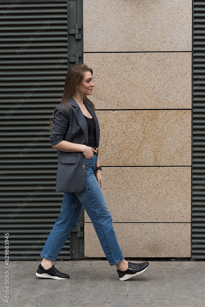 Portrait of a happy smiling woman in casual clothes while walking around the city.