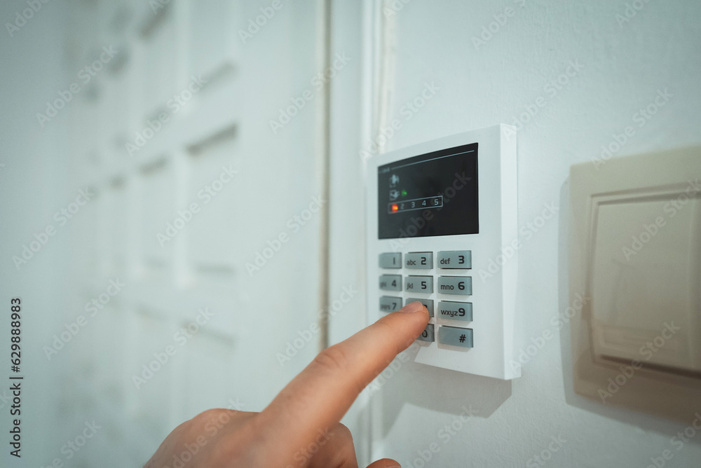 Man putting code in alarm system panel at home.