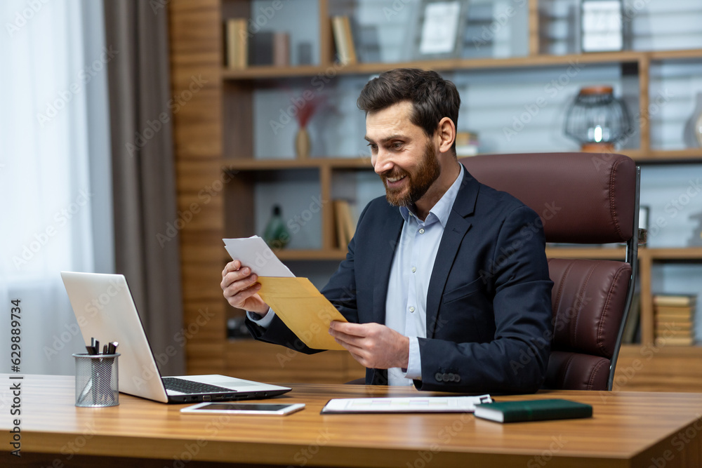 Happy successful boss received mail notification envelope with good news message, financier at workplace inside office, businessman happy with successful delivery results.