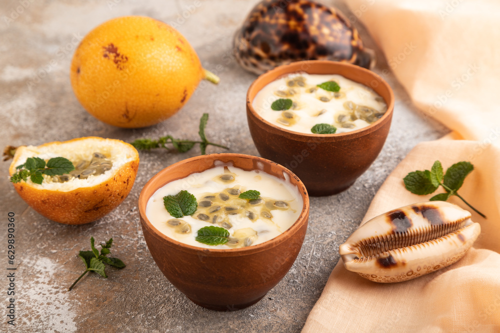 Yoghurt with granadilla and mint in clay bowl on brown concrete, side view Yoghurt with granadilla and mint in clay bowl on brown concrete, side view