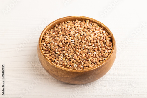 Raw buckwheat on white wooden, side view